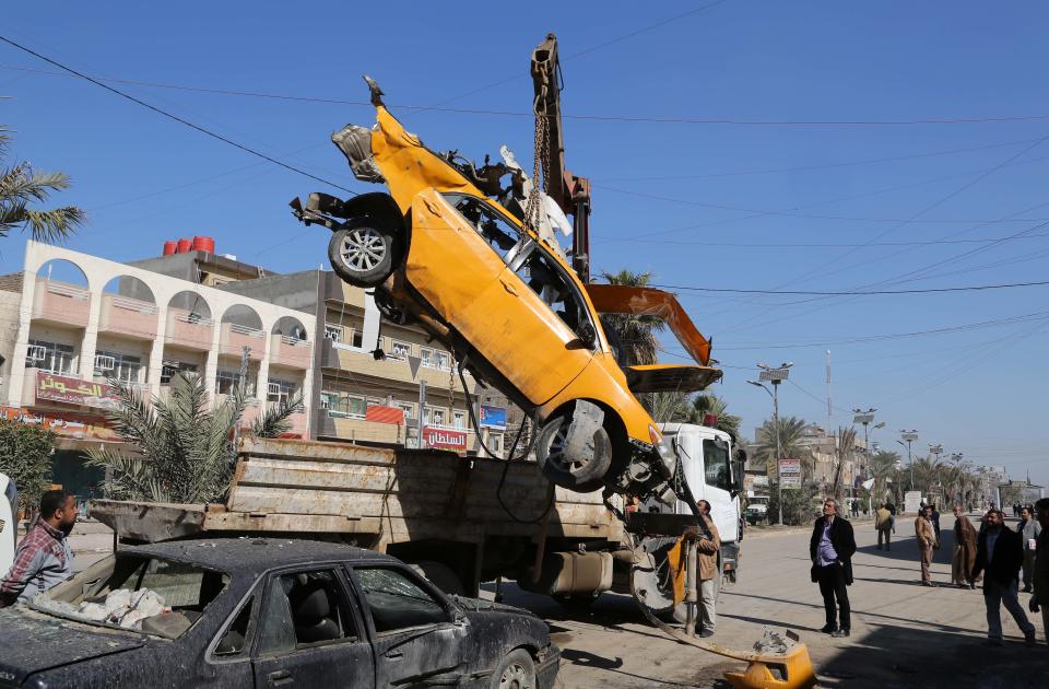 A wrecked car is removed from the site of a car bomb attack in the Shaab neighborhood of Baghdad, Iraq, Thursday, Feb. 6, 2014. A string of car bomb attacks hit commercial areas in Baghdad on Thursday, killing and wounding scores of people, said Iraqi officials. (AP Photo/Karim Kadim)