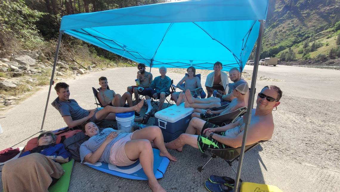 Jennifer Gleason’s rafting group sits under a tarp at the Carey Creek boat ramp on the Main Salmon River on July 8. The group paid Wild River Shuttle to drop off four vehicles, but only one was delivered.