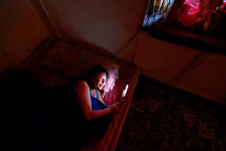 Drayang dancer Lhaden, 38, checks her mobile phone as she rests at home in the capital city of Thimphu, Bhutan, December 16, 2017. Lhaden, a divorced mother-of-two, dances until midnight, and like thousands of her compatriots, is struggling to make ends meet. "I'm not happy or sad about things, I have no other choice," she said. Lhaden, who earns $125 a month, is counting the pennies. "I live in such a small flat so I can afford food and clothes." REUTERS/Cathal McNaughton