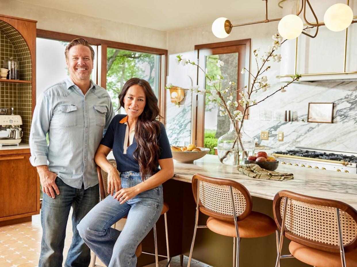 Chip and Joanna Gaines pose next to a large kitchen island.