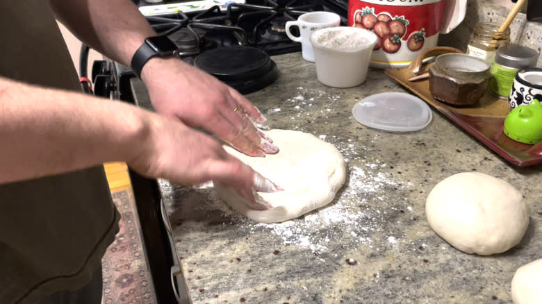 Patting pizza dough with hands 