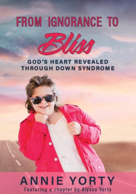 Alyssa Yorty is pictured on the cover of the book ‘From Ignorance to Bliss: God’s Heart Revealed Through Down Syndrome’ by her mother Annie. The road represents the journey they are on.