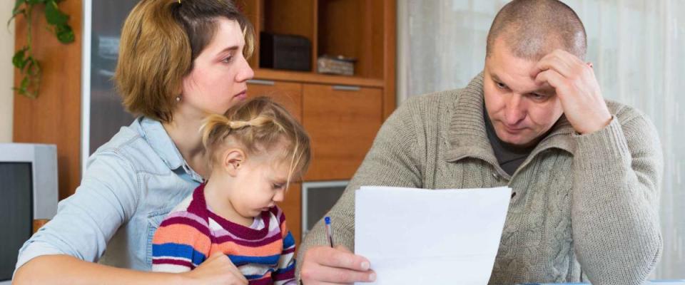 Serious couple with little girl counting budget at home