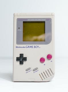 An original Game Boy console in grey with red buttons.