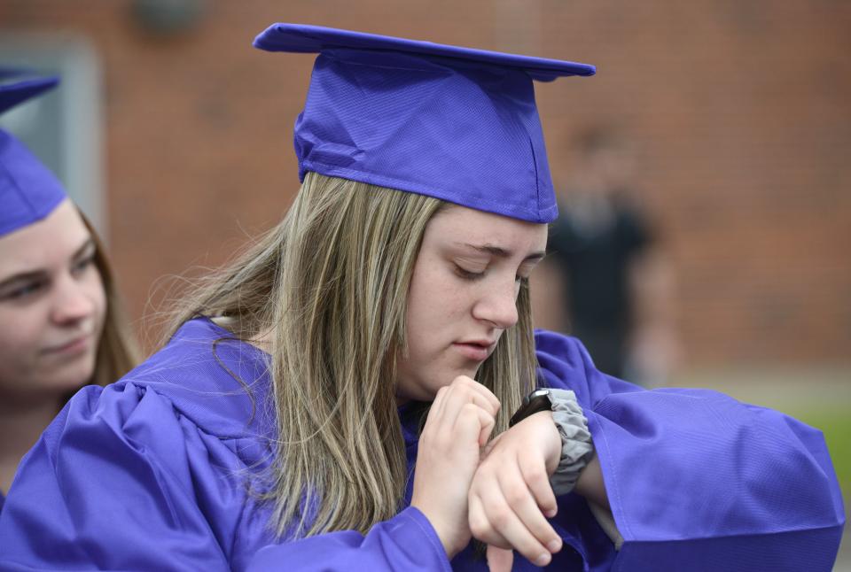 Senior Savannah Kelley checks the time before stepping off with classmates outside the Bourne Intermediate School where the grade schoolers ringed the school to cheer on this year's Class of 2022. Steve Heaslip/Cape Cod Times