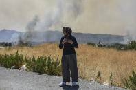 A woman looks at the wildfires in Kacarlar village near the Mediterranean coastal town of Manavgat, Antalya, Turkey, Saturday, July 31, 2021. The death toll from wildfires raging in Turkey's Mediterranean towns rose to six Saturday after two forest workers were killed, the country's health minister said. Fires across Turkey since Wednesday burned down forests, encroaching on villages and tourist destinations and forcing people to evacuate.(AP Photo)