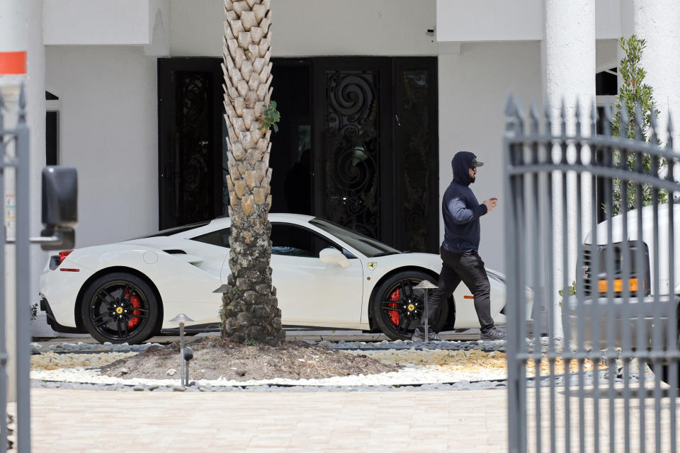 Un hombre pasa frente a un Ferrari en la entrada de la casa de Sean Kingston en el suburbio de Southwest Ranches, Florida, el jueves 23 de mayo de 2024. Policía especializada allanó la mansión alquilada del rapero Kingston en el sur de Florida y arrestó a su madre por cargos de fraude y robo que, según un abogado, se deben en parte a la instalación de un televisor enorme en su casa. (Amy Beth Bennett/South Florida Sun-Sentinel vía AP)