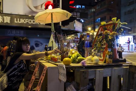 A demonstrator offers incense at a makeshift altar on a road blocked by protesters at the Mongkok shopping district in Hong Kong October 10, 2014. REUTERS/Tyrone Siu