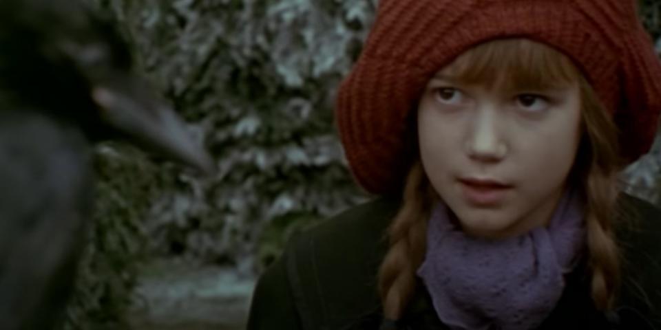 Mary looks at a crow while standing in a frost-covered garden