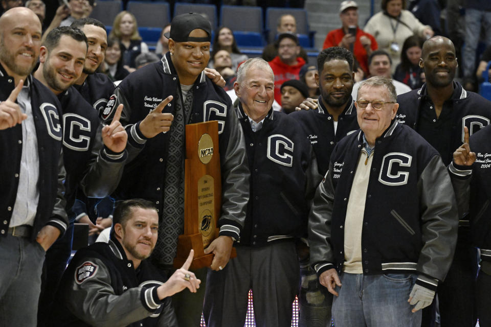 Former UConn head coach Jim Calhoun, center, stands with players and coaches from the 2004 national championship team during halftime ceremony at an NCAA college basketball game against Xavier, Sunday, Jan. 28, 2024, in Hartford, Conn. (AP Photo/Jessica Hill)