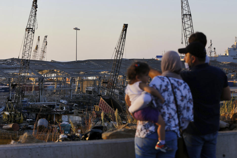 A family looks at the aftermath of the site of the Aug. 4 explosion that hit the seaport of Beirut, Lebanon, Sunday, Aug. 16, 2020. (AP Photo/Bilal Hussein)