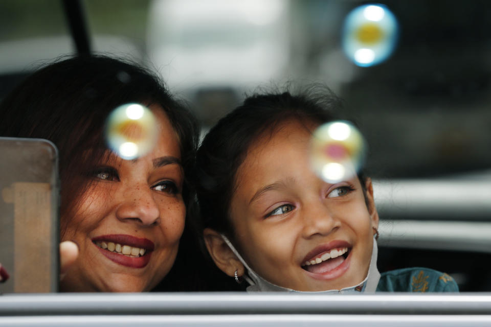 FILE - A woman and child peer out their car window as bubbles are blown into their car by volunteers from the Muslim Community Center as part of an Eid al-Fitr ceremony celebrating the end of Ramadan and a month of fasting in the Sunset Park neighborhood of Brooklyn, Sunday, May 24, 2020, in New York. Because of the need for social distancing due to coronavirus, the celebration was a drive-by celebration in which sweets and toys were handed out. (AP Photo/Kathy Willens, File)