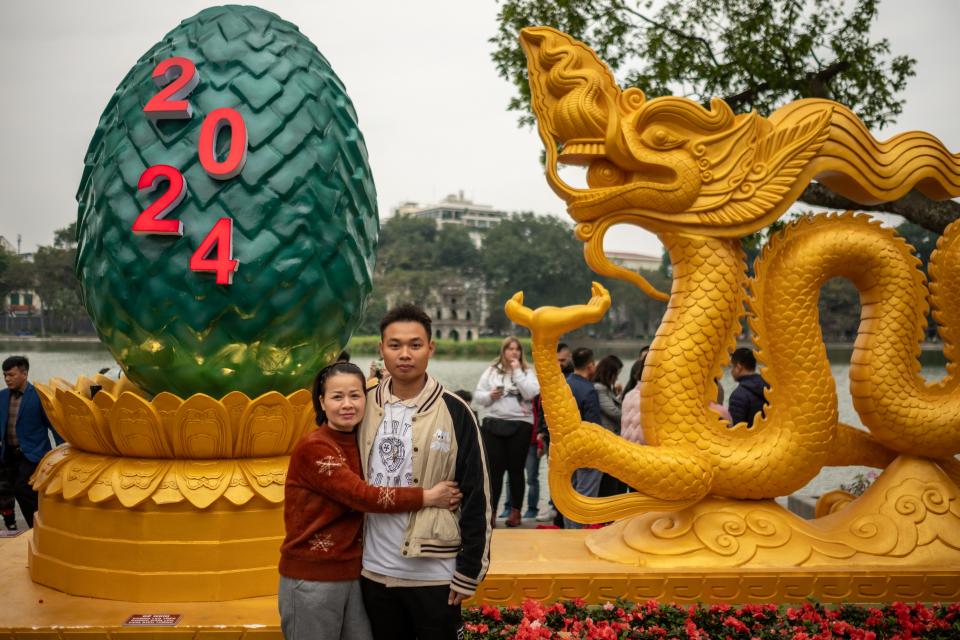 People pose for photos with a golden dragon statue at Hoan Kiem lake on February 9, 2024 in Hanoi, Vietnam.