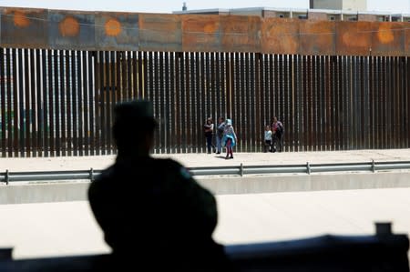 A member of the Mexican National Guard observes migrants after they illegally crossed into El Paso, Texas, U.S., to request asylum, as seen from Ciudad Juarez