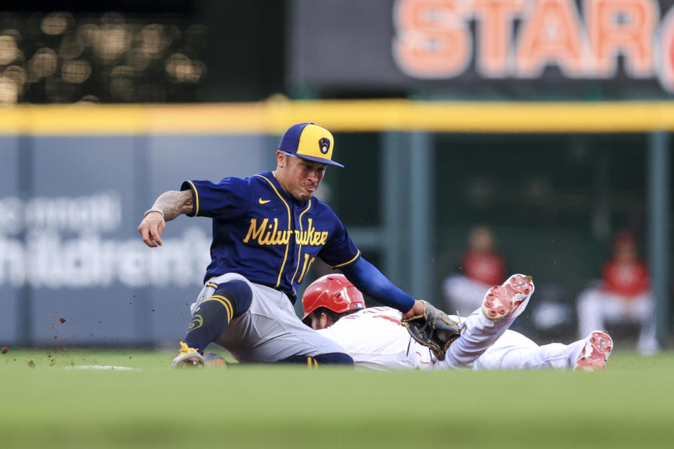 Milwaukee Brewers' Kolten Wong, left, tags out Cincinnati Reds' Tyler Naquin as he attempts to steal second base during the fourth inning of a baseball game in Cincinnati, Monday, May 9, 2022. (AP Photo/Aaron Doster)