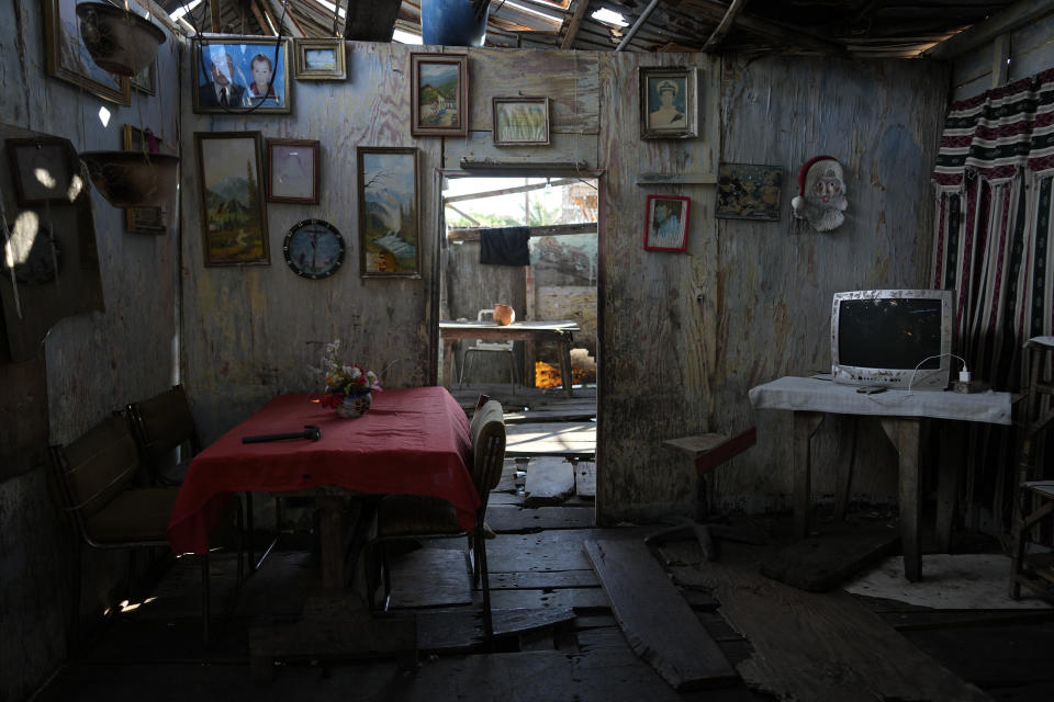 Retratos de familia y cuadros adornan las paredes de una casa sobre pilones que se asienta en la orilla del Lago de Maracaibo en el barrio de Santa Rosa de Agua de Maracaibo, Venezuela, el martes 8 de agosto de 2023. (AP Foto/Ariana Cubillos)