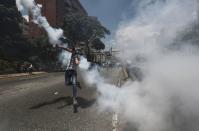 A demonstrator throws back a tear gas grenade launched by the Bolivarian National Police during a protest in Caracas, Venezuela, Saturday, April 8, 2017. Opponents of President Nicolas Maduro protest on the streets of Caracas on Saturday as part of a week-long protest movement that shows little sign of losing steam. (AP Photo/Fernando LLano)