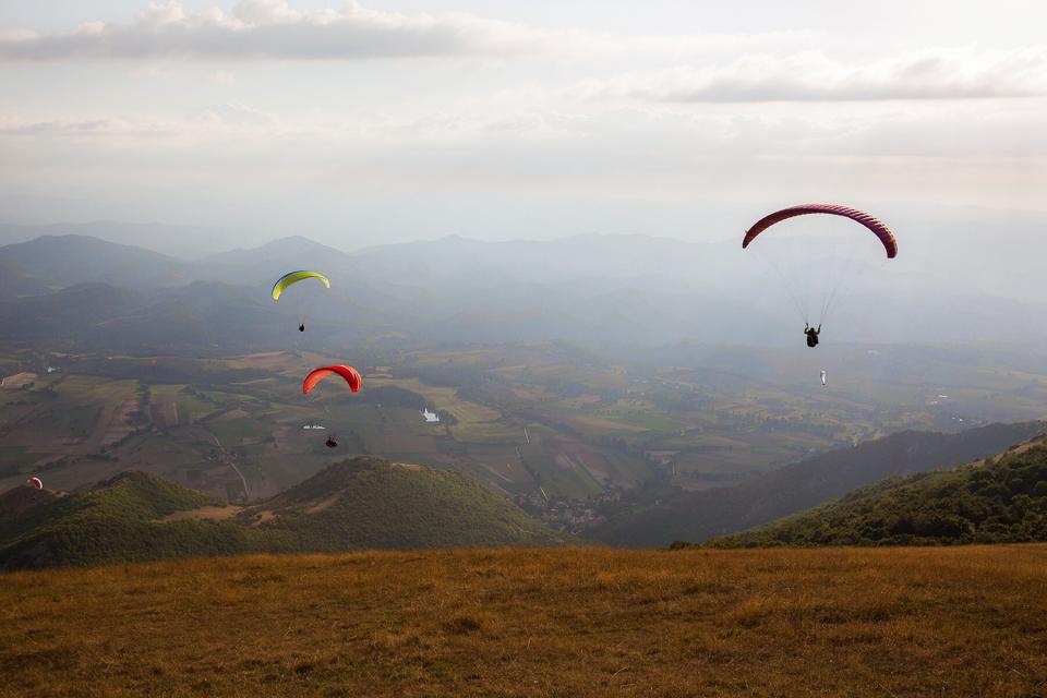 Paragliders flying over a mountain scenery in Umbria