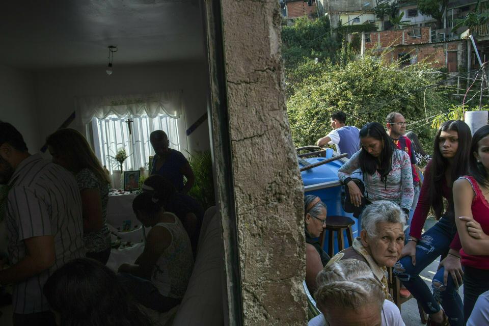 Un grupo de gente se reúne en la casa de Nick Samuel Oropeza para rezar por él en Caracas, Venezuela, el 3 de febrero de 2019. El joven, de 19 años, fue hallado en el piso, con la camiseta cubierta de sangre, el 23 de enero luego de que la policía nacional disparó contra manifestantes antigubernamentales, según cuenta su familia. (AP Foto/Rodrigo Abd)