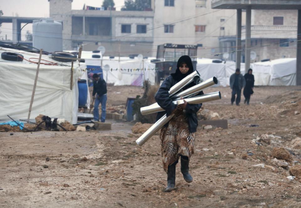 A Syrian refugee, who fled the violence from her country, holds pipes used for a fireplace in preparation for a storm, at the Lebanese border town of Arsal, in the eastern Bekaa Valley December 10, 2013. The Social Affairs Ministry announced Tuesday that it started to execute a plan for helping the displaced Syrians in Lebanon amidst the snow storm expected to strike Lebanon today evening, the National News Agency (NNA) reported. REUTERS/Mohamed Azakir (LEBANON - Tags: POLITICS CIVIL UNREST CONFLICT SOCIETY IMMIGRATION)