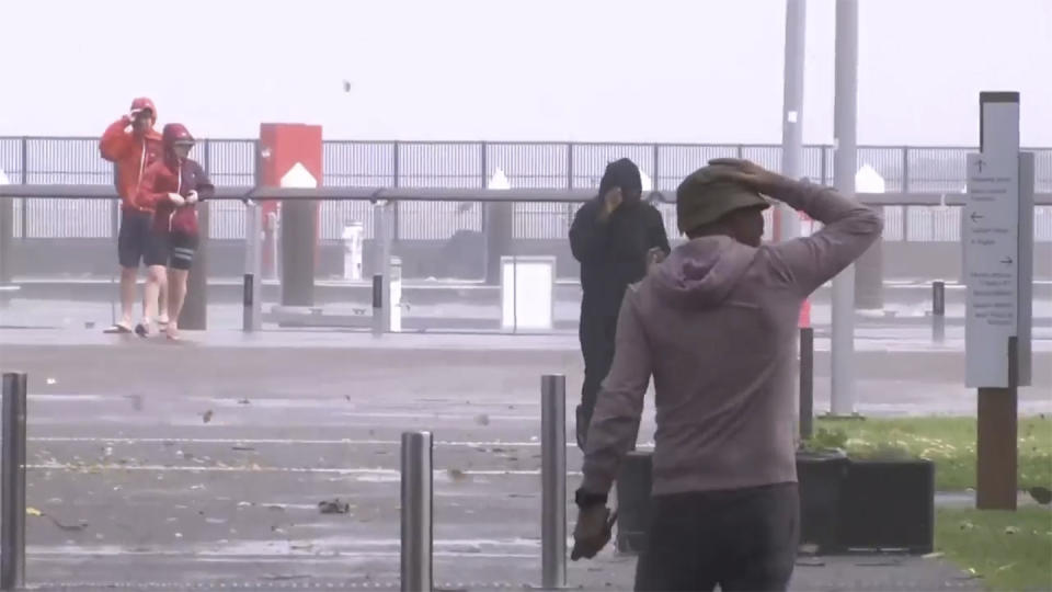 This image made from video show people walking through high winds in Cairns, Australia Wednesday, Dec. 13, 2023. Powerful winds began uprooting trees on the northeast Australian coast on Wednesday as Tropical Cyclone Jasper gathered strength while approaching the area. (Australian Broadcasting Corporation via AP)
