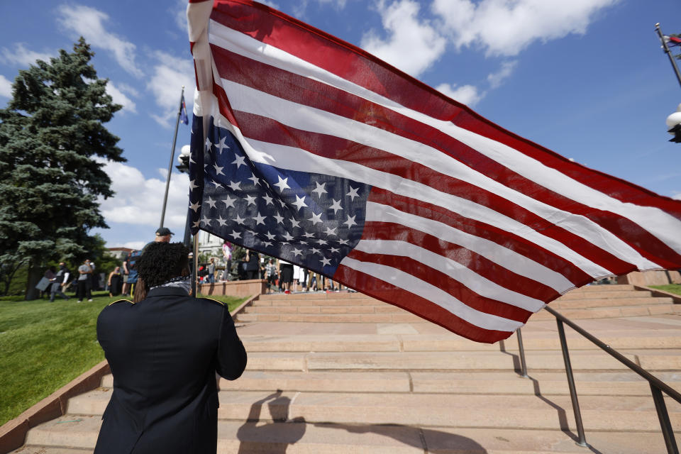 Aubrey Rose, who earned the rank of staff sergeant during four tours of duty in the U.S. Army, holds an American flag during a protest outside the State Capitol over the death of George Floyd, a handcuffed black man in police custody in Minneapolis, Thursday, May 28, 2020, in Denver. Close to 1,000 protesters walked from the Capitol down the 16th Street pedestrian mall during the protest. (AP Photo/David Zalubowski)