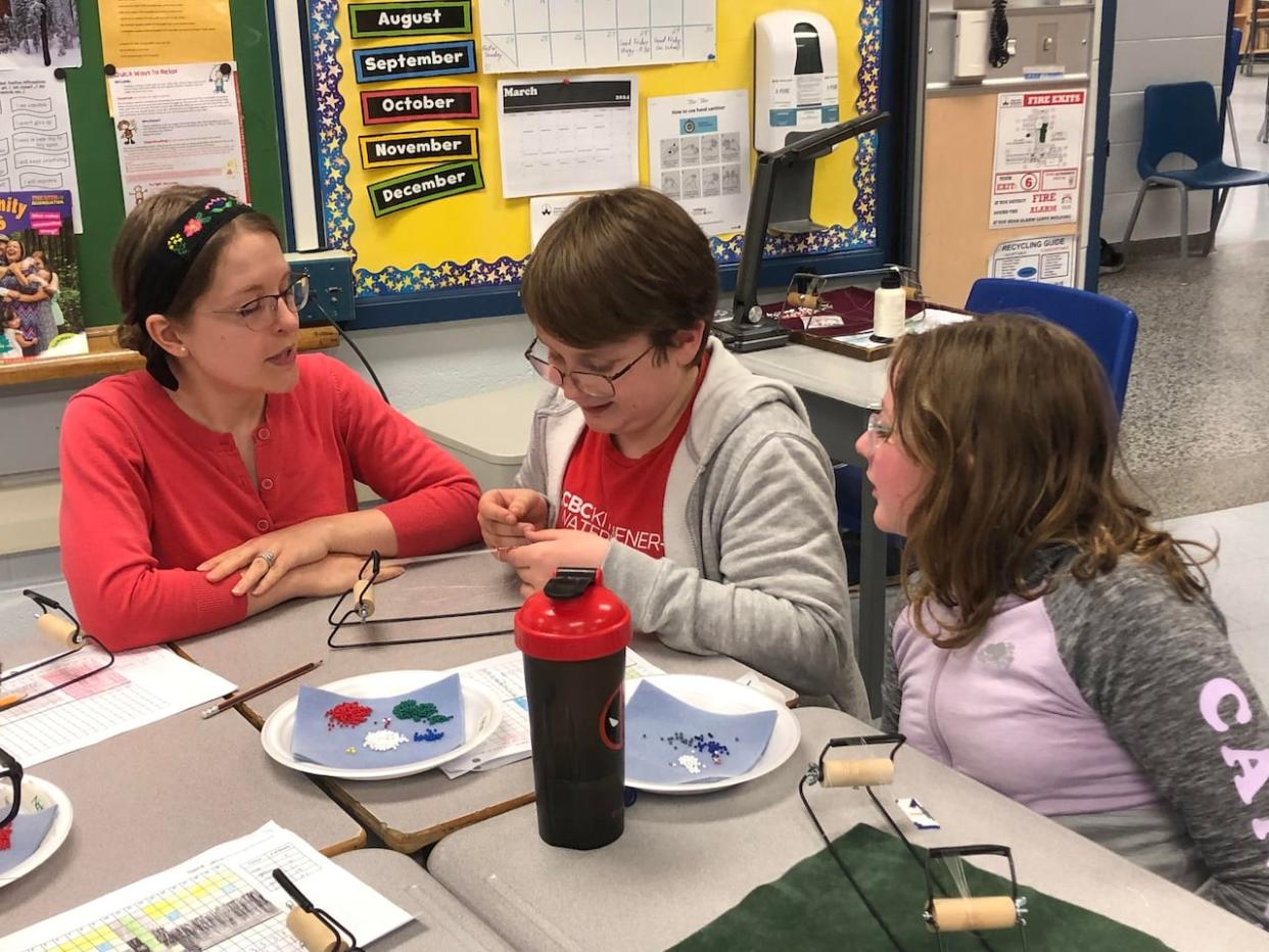 Grade 6 students at St. John Catholic Elementary School in Guelph, Ont., recently worked on bracelets with the help of Métis knowledge keeper Alicia Hamilton, left, as part of an elementary school initiative that explores math concepts while incorporating Indigenous practices. (Karis Mapp/CBC - image credit)