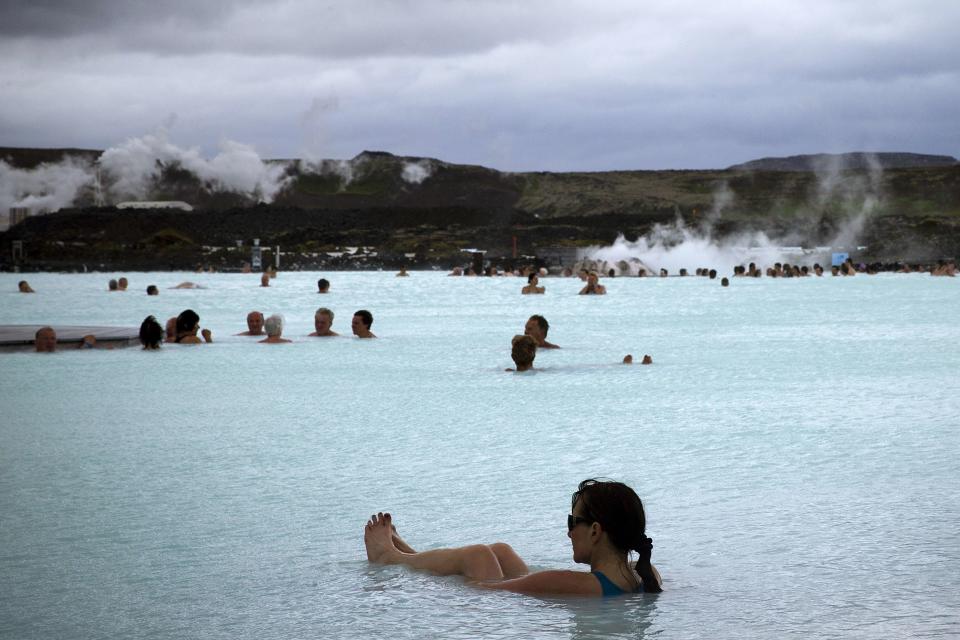 People bathe in the "Blue Lagoon" geothermal spa, one of the most visited attractions in Iceland in the Reykjanes Peninsula, Southwestern Iceland on July 5, 2014. The spa is located on a lava field.