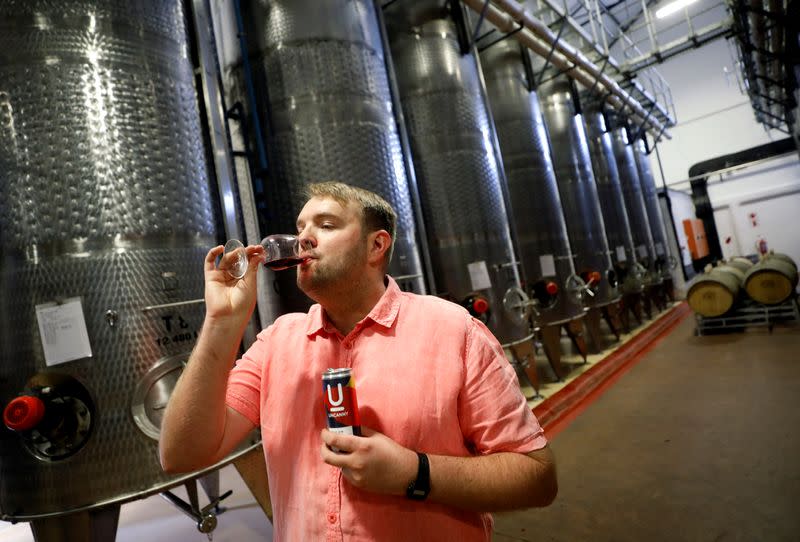 El copropietario de Uncanny Wines, Arnold Vlok, prueba un vaso de Merlot, parte de la serie de vinos enlatados de la compañía, en Paarl