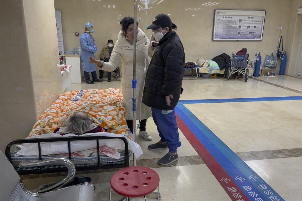 Women chat as elderly patients on stretchers receive treatment in the hallway of an emergency ward in Beijing, Thursday, Jan. 19, 2023. China on Thursday accused "some Western media" of bias, smears and political manipulation in their coverage of China's abrupt ending of its strict "zero-COVID" policy, as it issued a vigorous defense of actions taken to prepare for the change of strategy. (AP Photo/Andy Wong)