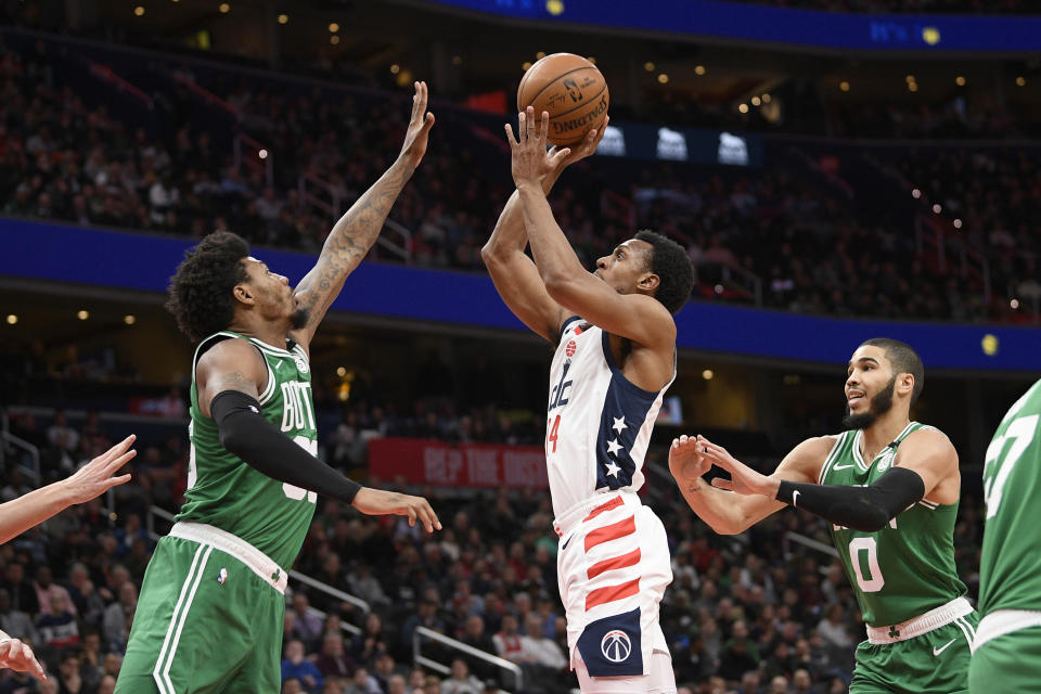 Washington Wizards guard Ish Smith, center, shoots between Boston Celtics guard Marcus Smart, left, and forward Jayson Tatum (0) during the first half of an NBA basketball game, Monday, Jan. 6, 2020, in Washington. The Wizards won 99-94. (AP Photo/Nick Wass)