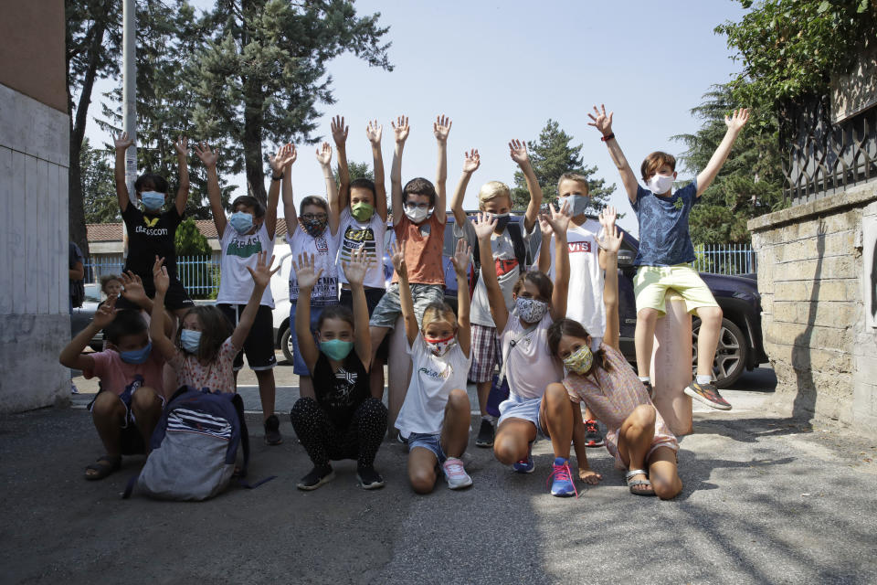 Children of the Mario Lodi primary school pose for group photo wearing masks to protect against COVID-19, at the end of their first day of school, in Rome, Tuesday, Sept. 15, 2020. The reopening of Italian schools marks an important step in a return to pre-lockdown routine after six long months, long after the buzz returned to shopping malls, theaters and beaches, and another test of the government’s management of the pandemic. (AP Photo/Alessandra Tarantino)