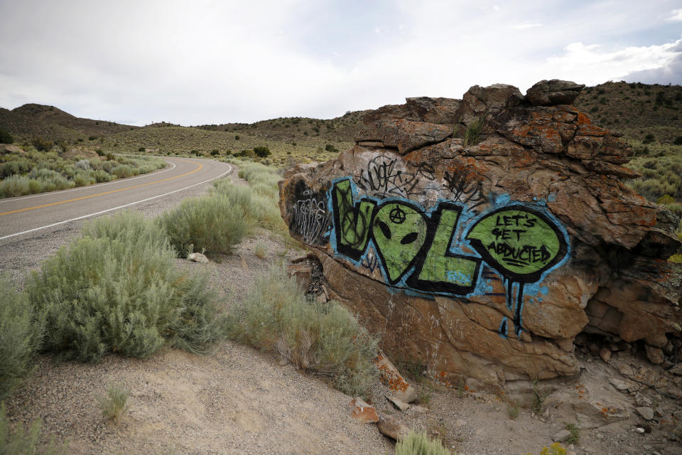 FILE - In this July 22, 2019 file photo, alien-themed graffiti adorns a rock along the Extraterrestrial Highway, near Rachel, Nev., a town close to the Nevada Test and Training Range near Area 51. Officials in Nevada's rural Lincoln County have drafted an emergency declaration and are planning with state officials to handle possible crowds that might arrive for an event next month dubbed "Storm Area 51." The county commission on Monday, Aug. 19, 2019 conditionally approved two events in tiny desert towns near the site popularly known as the home of government studies of outer space aliens. (AP Photo/John Locher, File)