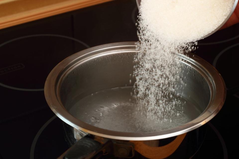 Pouring sugar into saucepan with boiling water