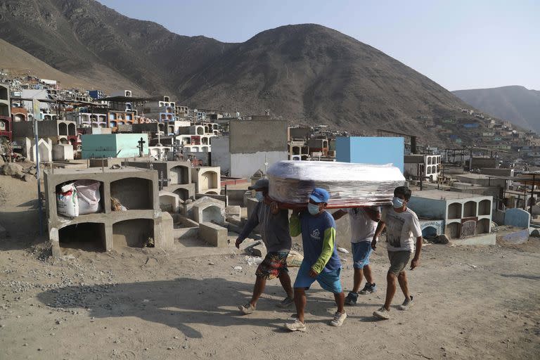 Trabajadores llevan el féretro que contiene los restos de una víctima de coronavirus en el cementerio informal "Mártires 19 de Julio" en el distrito de Comas, en las afueras de Lima, Perú, el país con más muertes de la región