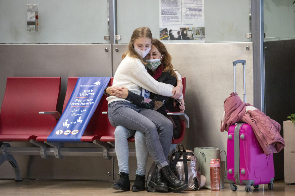 Passengers wear face masks to protect from coronavirus as they sit together in the departure hall in Ben Gurion Airport near Tel Aviv, Israel, Sunday, Jan. 24, 2021 during a nationwide lockdown to curb the spread of the virus COVID-19. Prime Minister Benjamin Netanyahu on Sunday said Israel was closing its international airport to nearly all flights as the government races to bring a raging coronavirus outbreak under control. (AP Photo/Ariel Schalit)