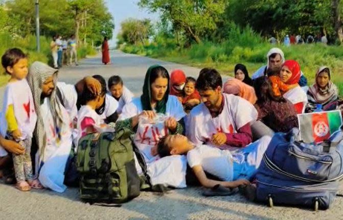 Merhia and Fahim Baraki, center, sprinkle water on their son in the midday heat of Islamabad, Pakistan, June 20, 2022, during a protest by hundreds of Afghan refugee families demanding legal status as asylum seekers. / Credit: CBS/Sami Yousafzai