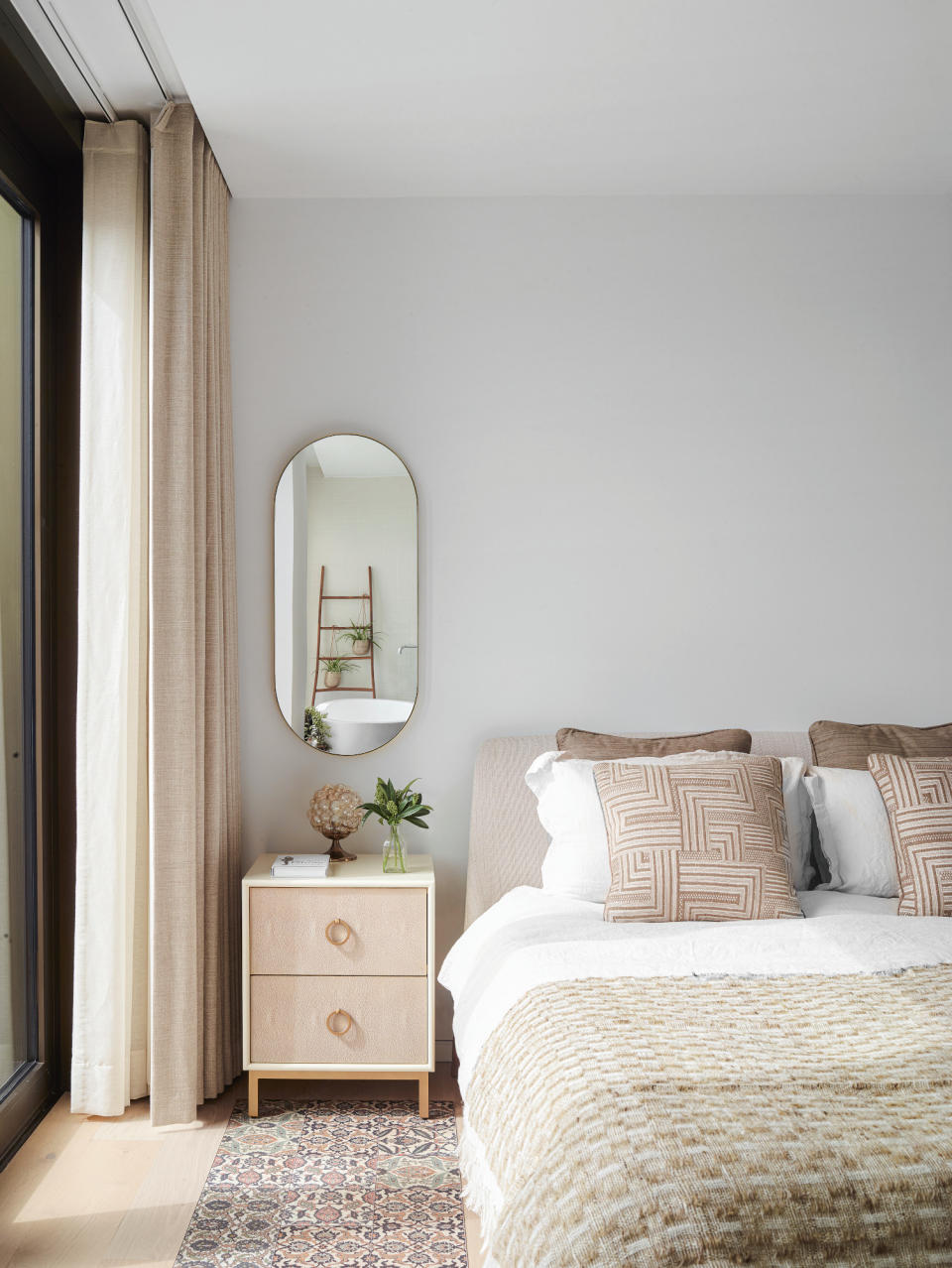 Bedroom with cool white walls, beige bedside table and beige bed frame