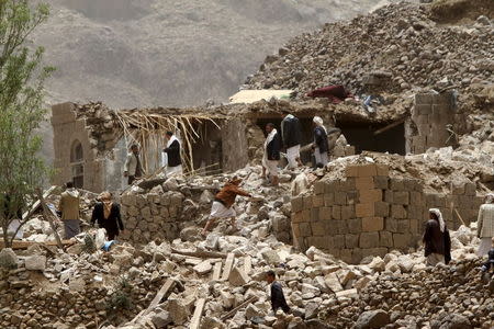 People stand on the rubble of houses destroyed by an air strike in Okash village near Sanaa April 4, 2015. REUTERS/Mohamed al-Sayaghi