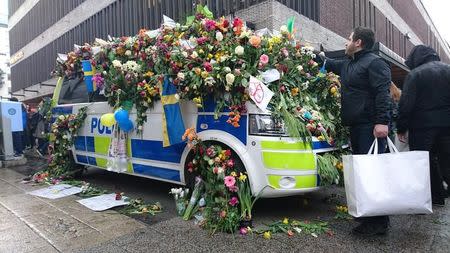 A man puts flowers on the police vehicle next to the Ahlens department store following Friday's attack in central Stockholm, Sweden, April 10, 2017. REUTERS/Philip O'Connor