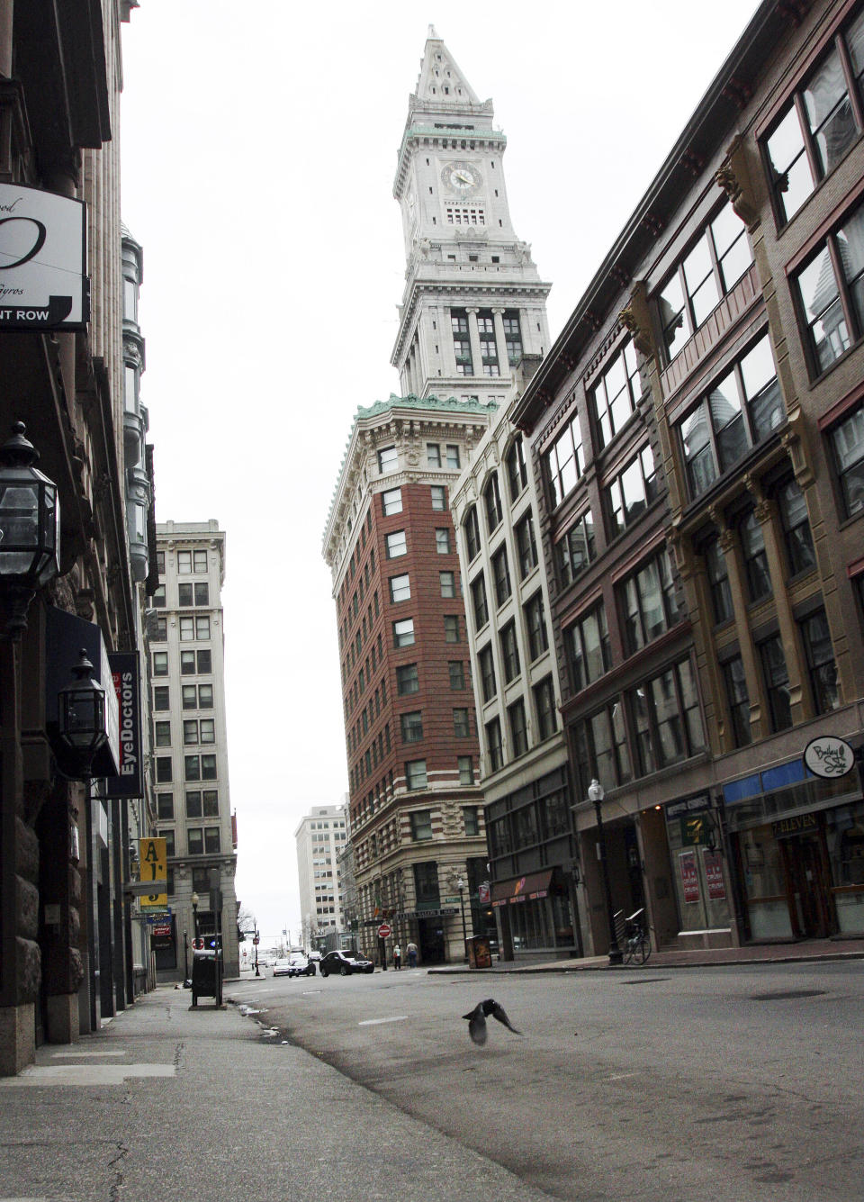 FILE - In this Friday, April 19, 2013 file photo, a pigeon flies along deserted State Street with the Custom House hotel in the background in downtown Boston. Mass transit was suspended while a suspect was hunted following bombings near the finish line of the Boston Marathon. (AP Photo/Bill Sikes, File)