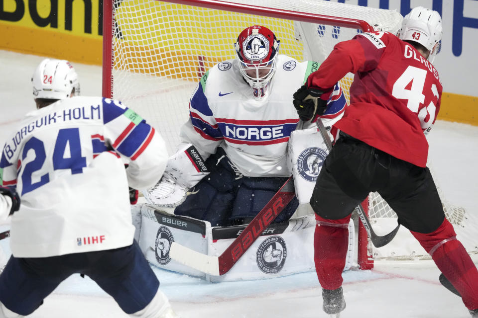 Goalie Jonas Arntzen of Norway fights for a puck with Andrea Glauser of Switzerland, right, during the group B match between Norway and Switzerland at the ice hockey world championship in Riga, Latvia, Sunday, May 14, 2023. (AP Photo/Roman Koksarov)