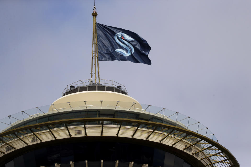 A flag with the new logo for the newly-named Seattle NHL team, the Seattle Kraken, flies atop the iconic Space Needle Thursday, July 23, 2020, in Seattle. The hockey expansion franchise unveiled its nickname Thursday, ending 19 months of speculation about whether the team might lean traditional or go eccentric with the name for the league's 32nd team. Seattle's colors are a deep dark blue with a lighter shade of blue as a complement. (AP Photo/Elaine Thompson)