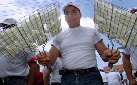 A Turkish Cypriot turns over pieces of Halloumi, a local cheese, in Ledra Street in central Nicosia, the world's last divided capital - Credit: AFP