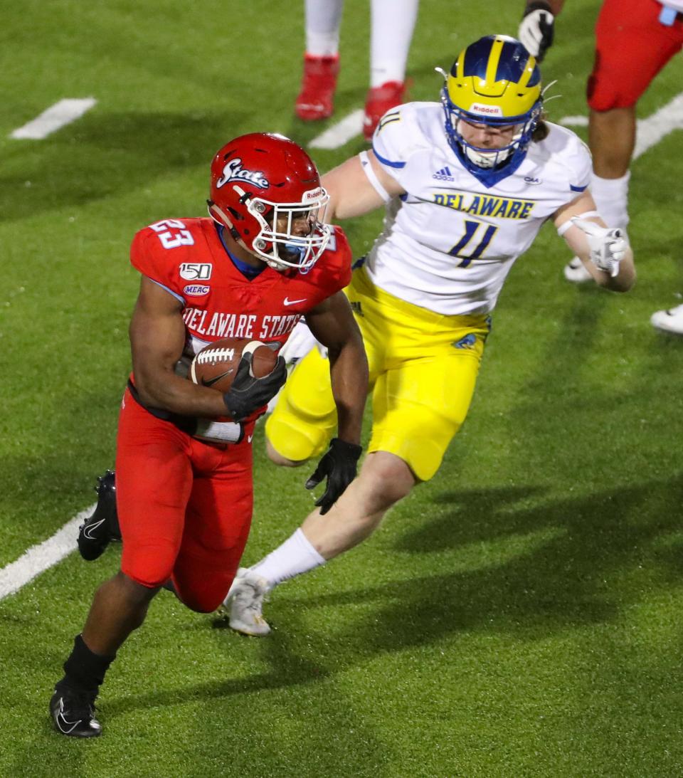Delaware State's Sy'veon Wilkerson is pursued by Delaware's Colby Reeder in the third quarter of the Blue Hens' 34-14 win at Alumni Stadium in Dover Saturday, April 10, 2021.