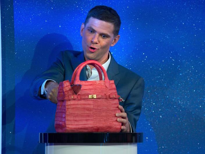 Mikey Day cutting a purse-shaped cake on is it cake