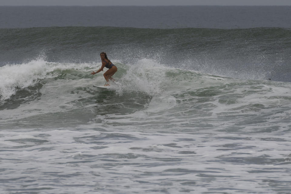 A woman surfs at El Tunco beach before the arrival of Hurricane Julia in La Libertad, El Salvador, Sunday, Oct. 9, 2022. Hurricane Julia hit Nicaragua's central Caribbean coast on Sunday after lashing Colombia's San Andres island, and a weakened storm was expected to emerge over the Pacific. (AP Photo/Moises Castillo)