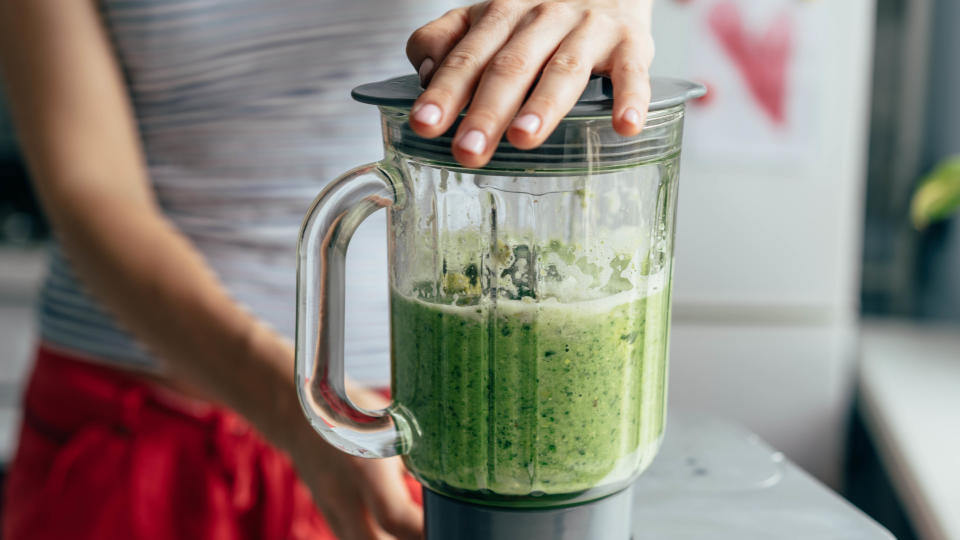 Someone holding the lid on a blender while it blends