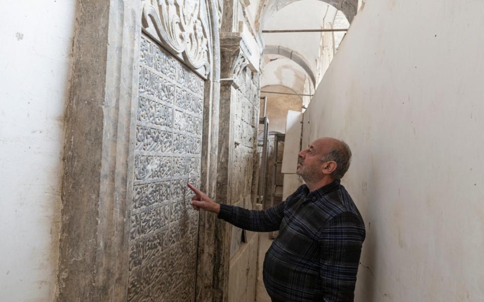 Saadullah Rassam, 63, who claims to be the only Christian currently living in the Old City of Mosul, looks at calligraphy inscribed on a tomb, in The Immaculate Syriac Catholic Church, in Mosul, Iraq, on March 4th 2021. - Sam Tarling for The Telegraph