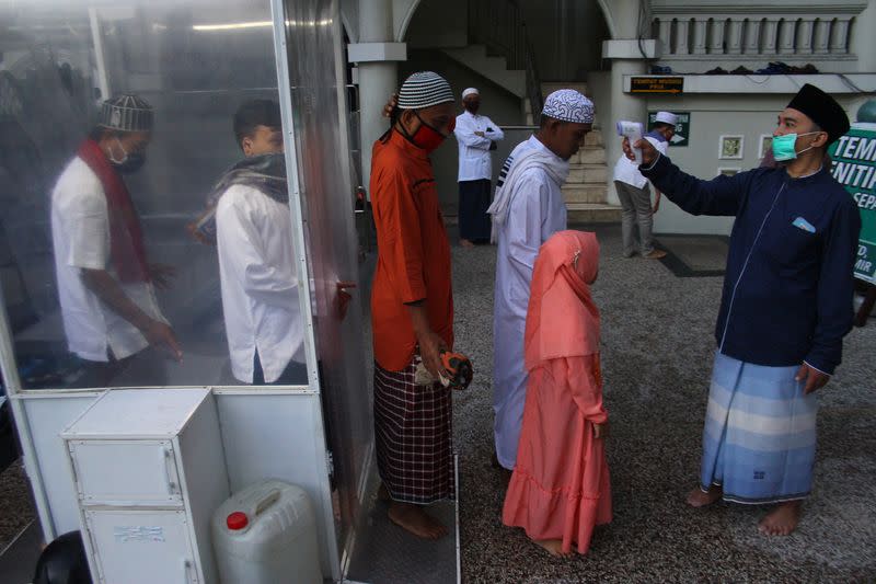 Indonesian Muslims have their body temerature checked before prayers for Eid al-Fitr, the Muslim festival marking the end the holy fasting month of Ramadan, at a mosque in Malang, East Java Province, Indonesia, amid the spread of coronavirus disease